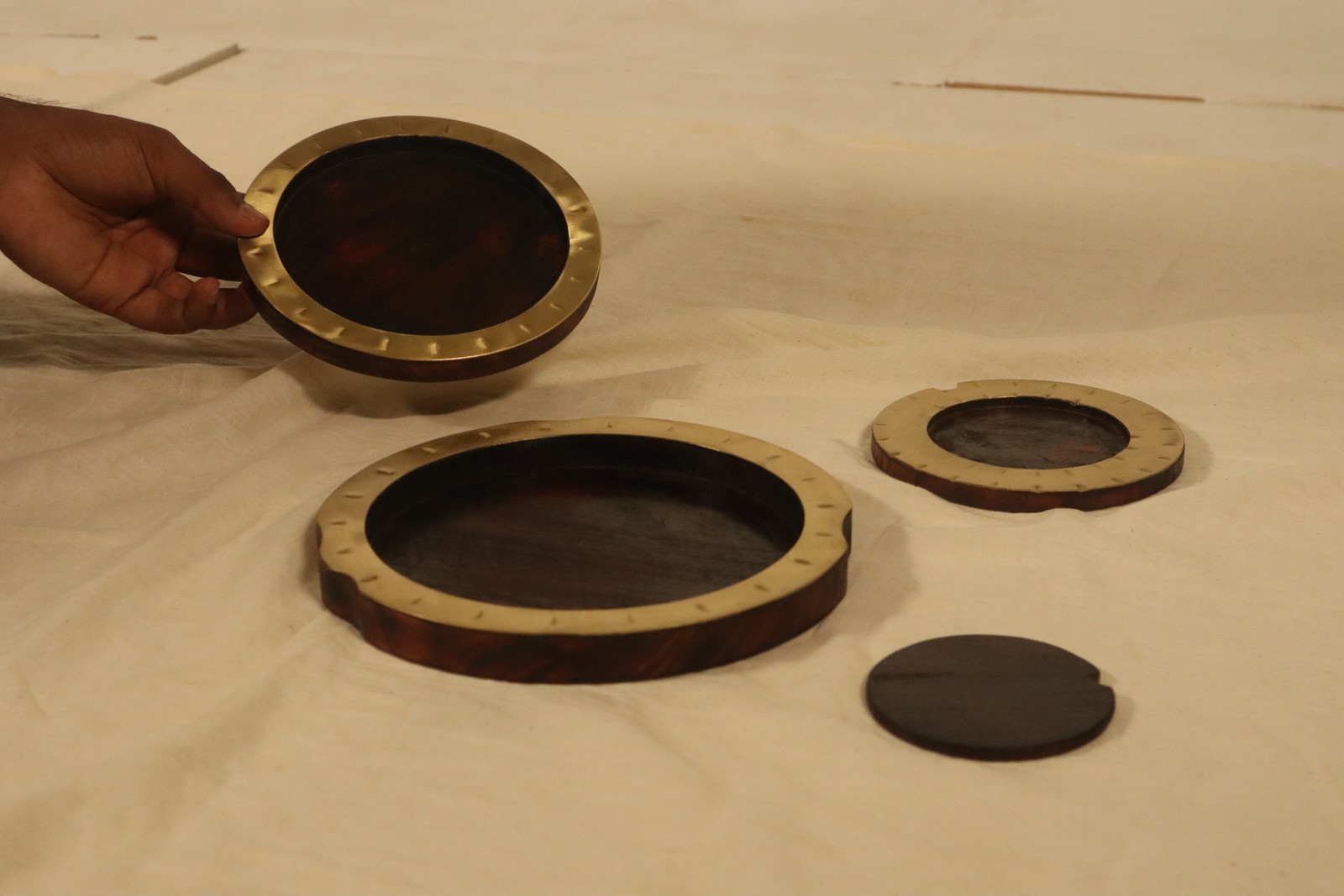 The four KOSH coasters unstacked on linen, one held in hand