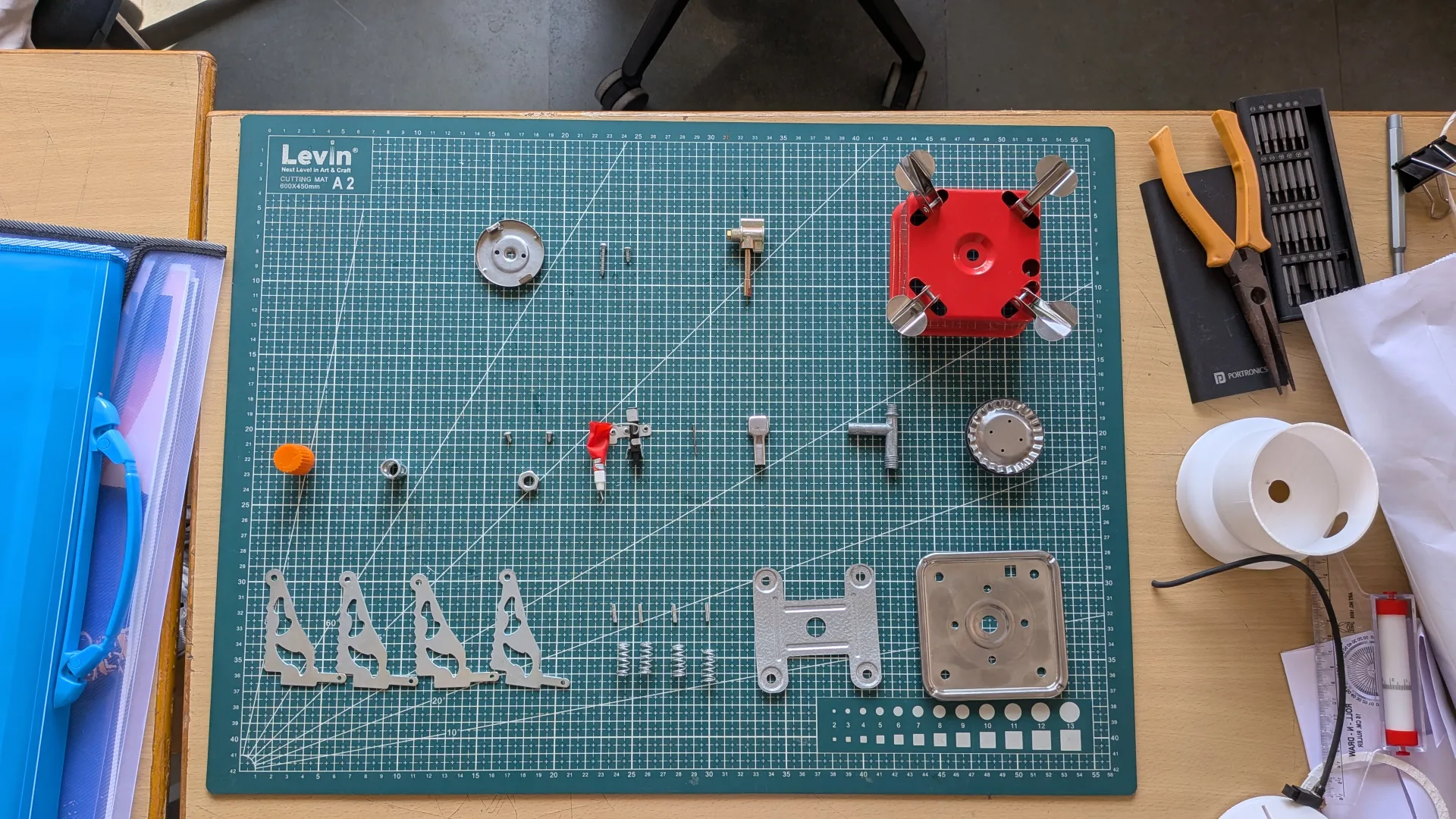 3D-printed and laser-cut prototype parts laid out on a green cutting mat